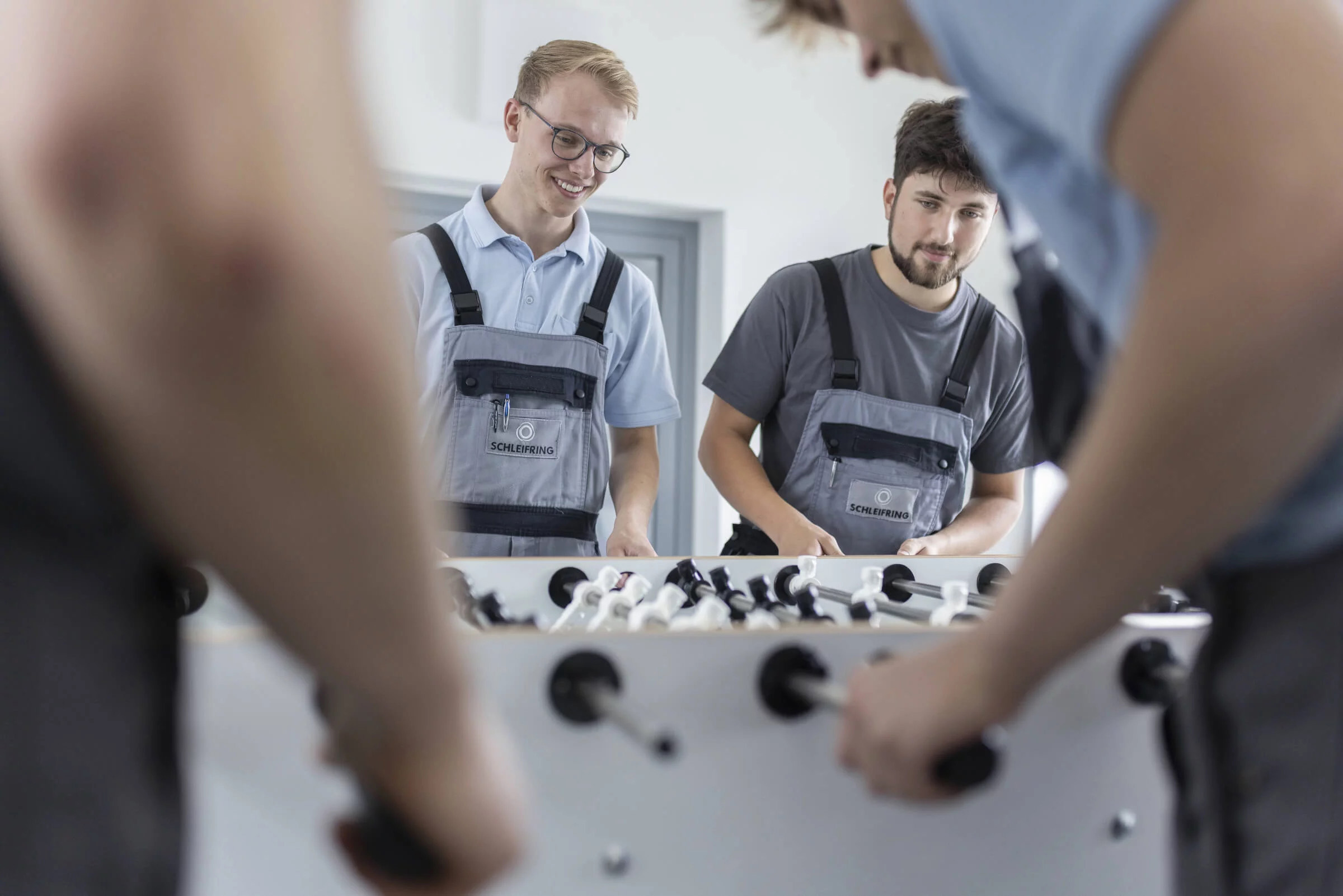 Auszubildende spielen gemeinsam Tischkicker in der Pause und haben sichtlich Spaß.