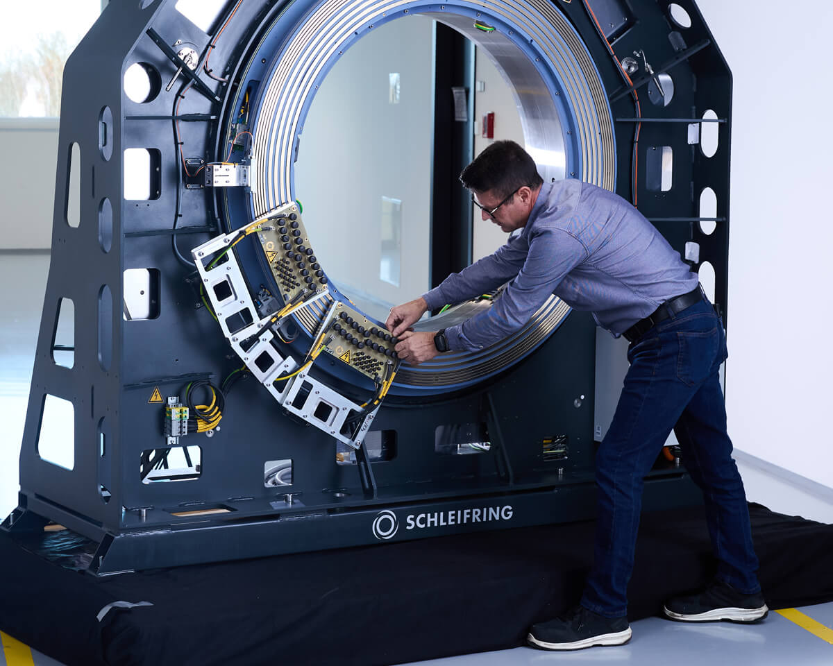 Techniker arbeitet an einem großformatigen CT-Schleifring im Test- oder Montagebereich.