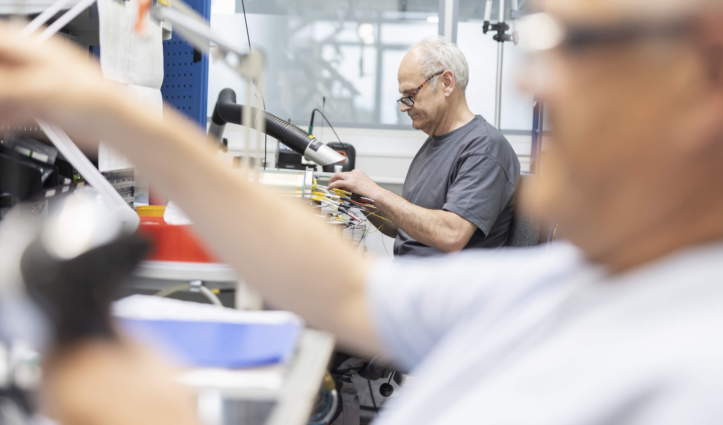 Zwei Mitarbeiter arbeiten an einem Arbeitsplatz für die Montage elektronischer Baugruppen.