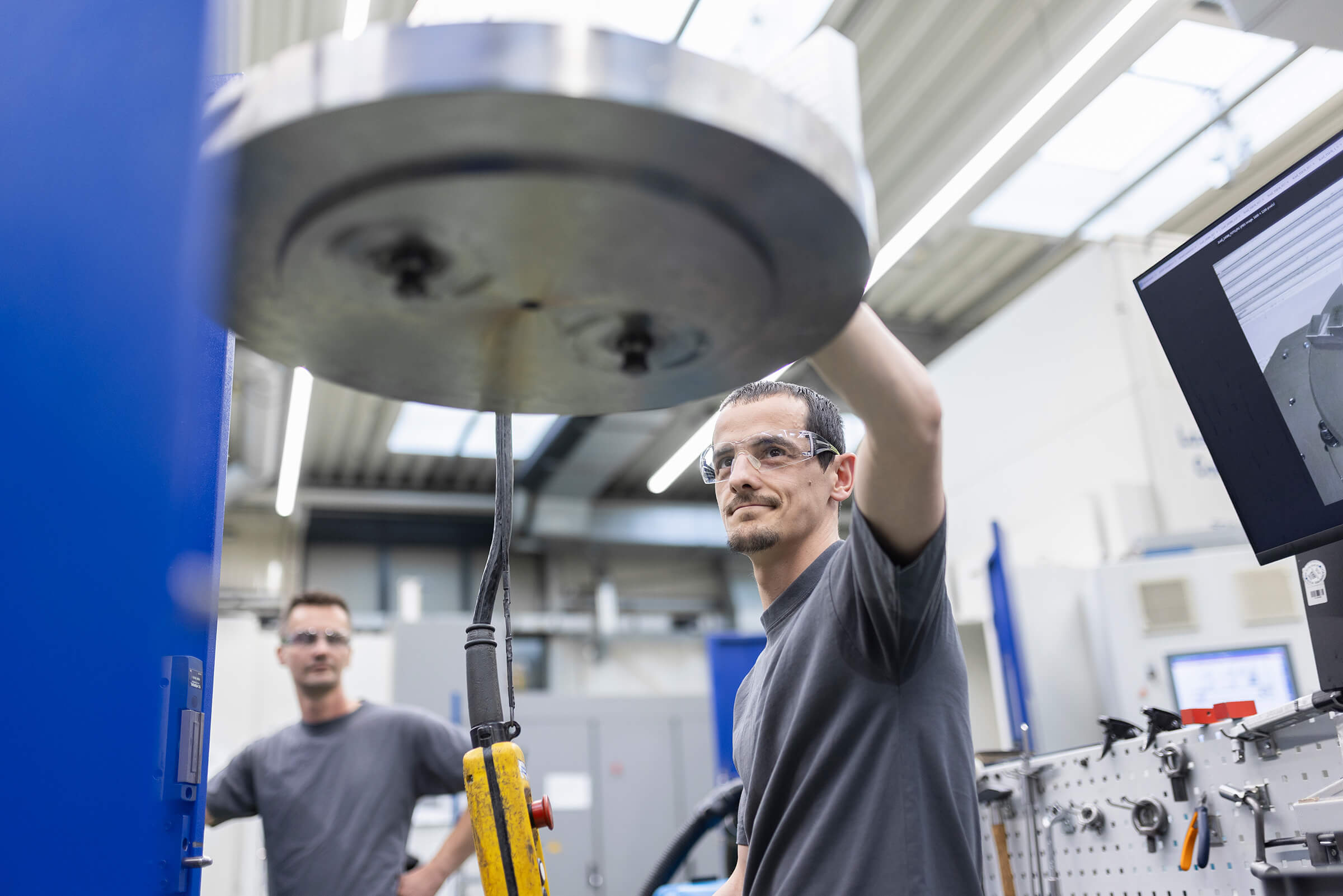 Ein SCHLEIFRING-Mitarbeiter bedient eine Industrie-Maschine in der Fertigung.