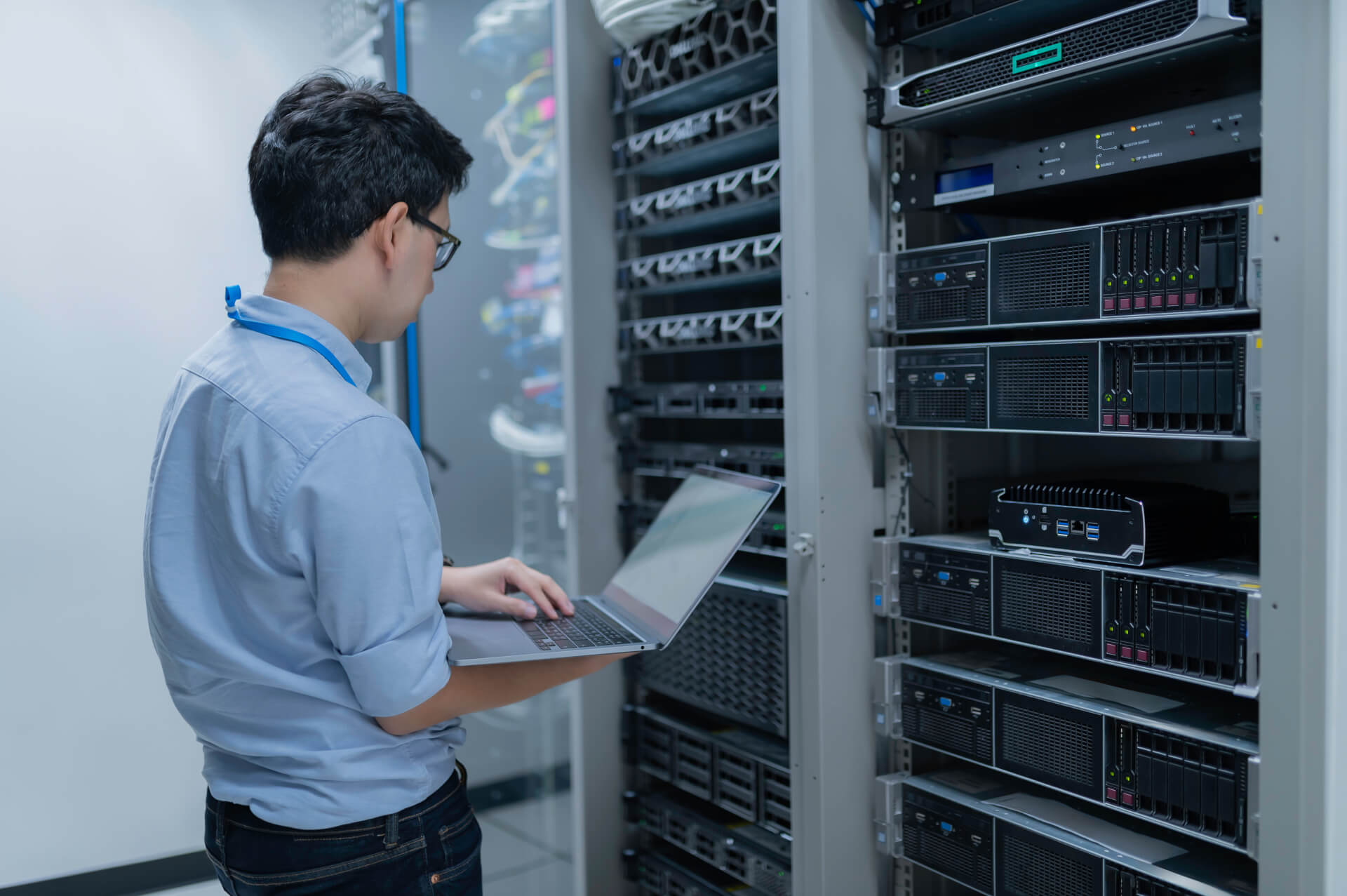 IT-Techniker arbeitet mit Laptop im Serverraum und überprüft die Systeme.