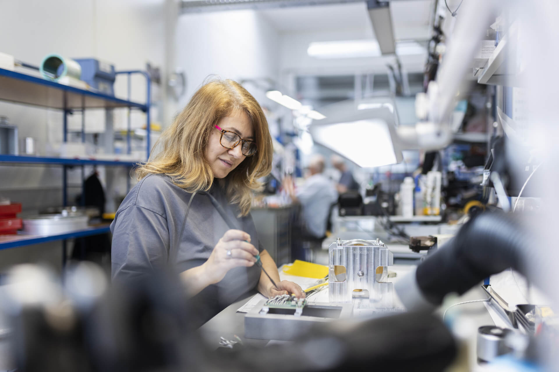 Mitarbeiterin arbeitet konzentriert an elektronischen Bauteilen in der Montage.