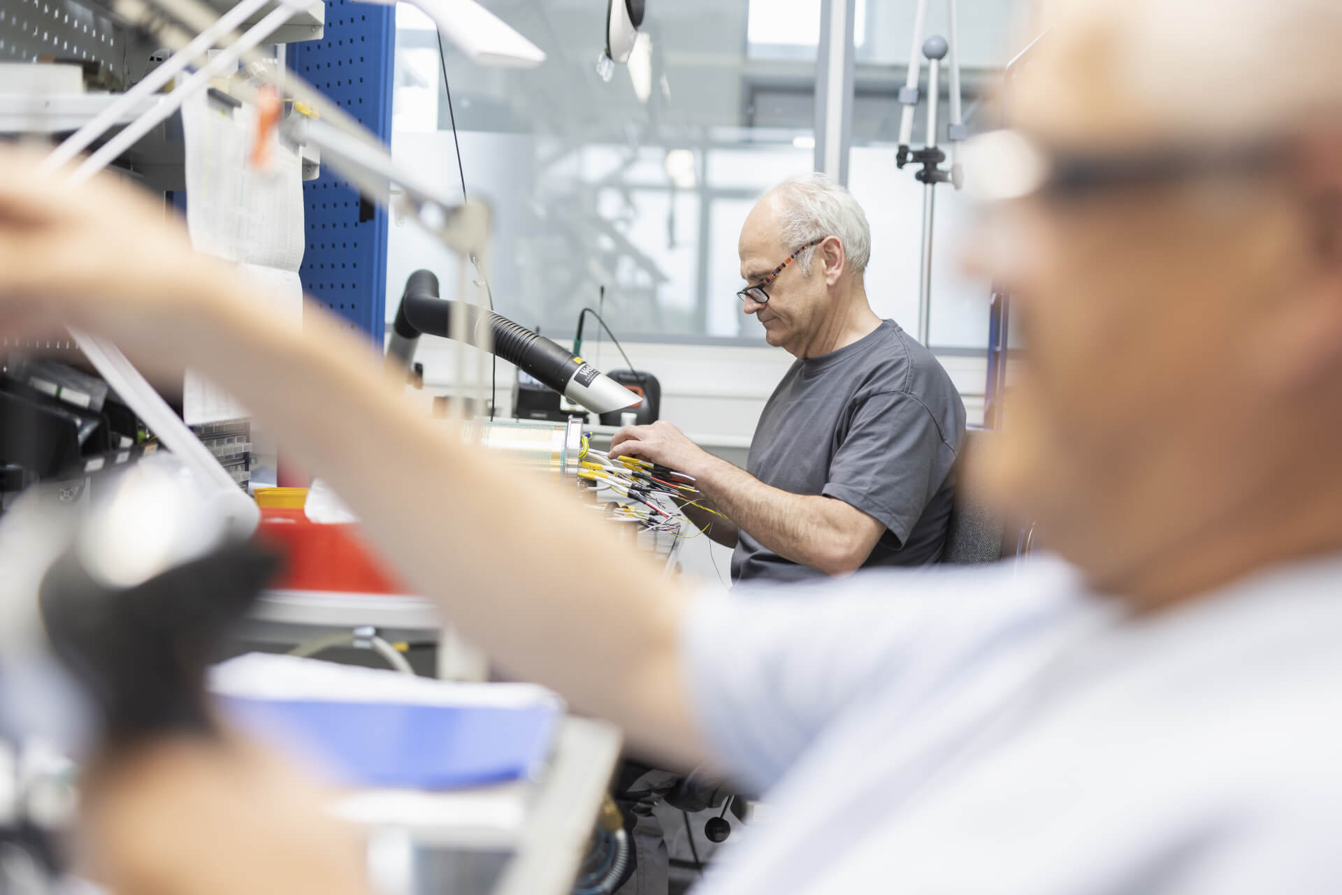 Zwei Mitarbeiter arbeiten an einem Arbeitsplatz für die Montage elektronischer Baugruppen.