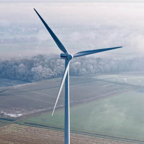 Windkraftanlage auf einem Feld aus der Vogelperspektive an einem nebligen Morgen