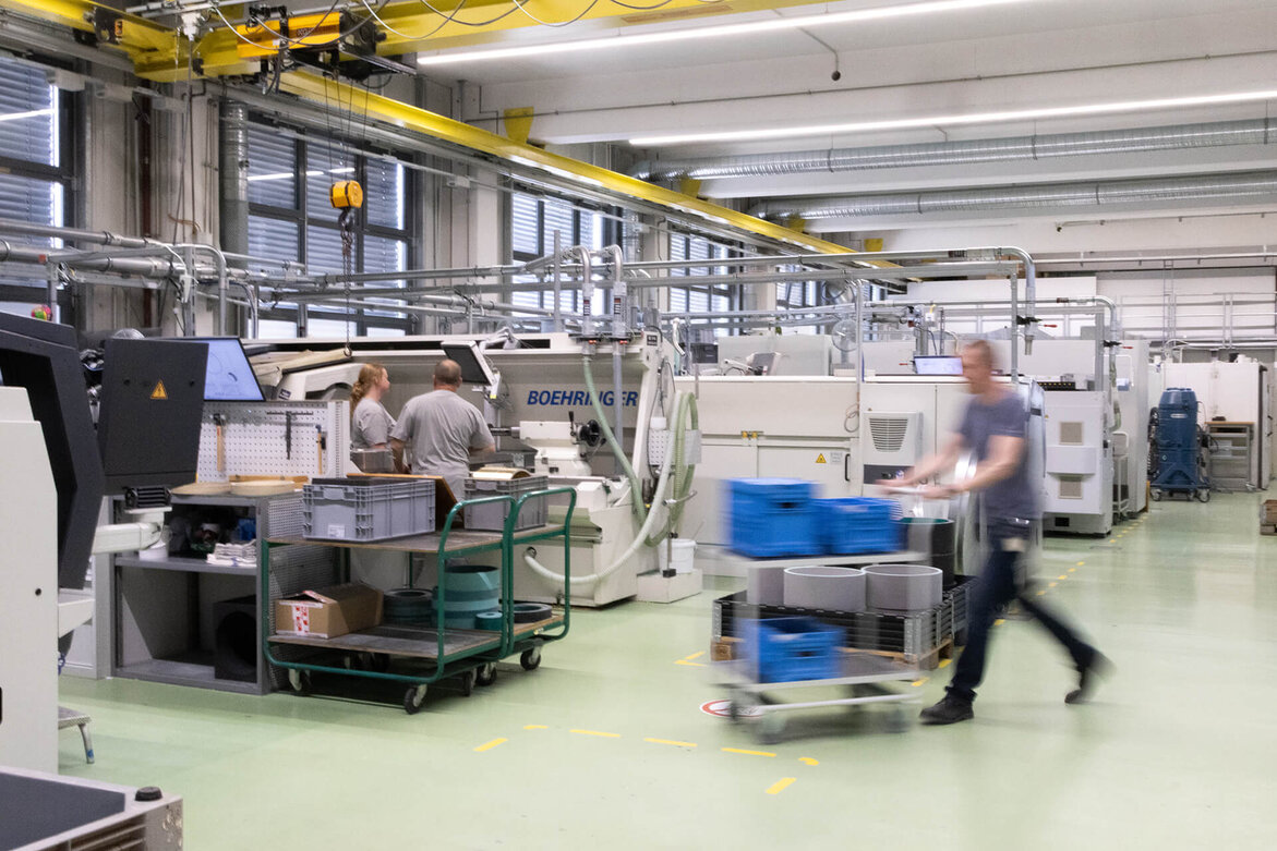 Mitarbeiter in einer modernen Industrieproduktionsanlage mit automatisierten Maschinen.