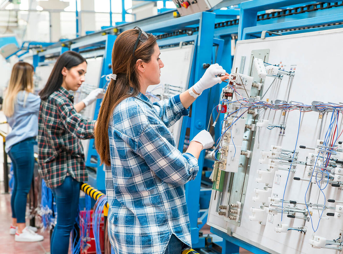 Mitarbeiterin arbeitet an einer Produktionslinie in einer Fabrik für Kabelkonfektion.
