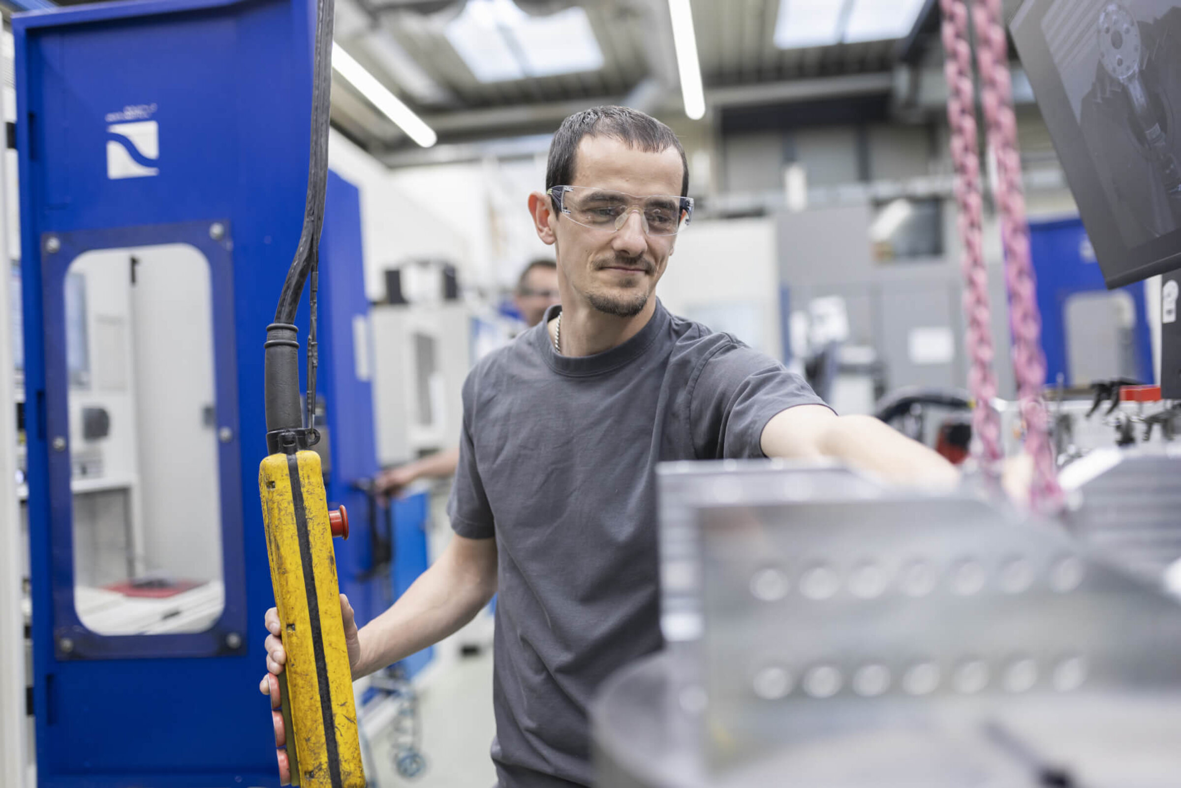 Mitarbeiter bedient konzentriert einen Hebekran in der Produktionshalle.