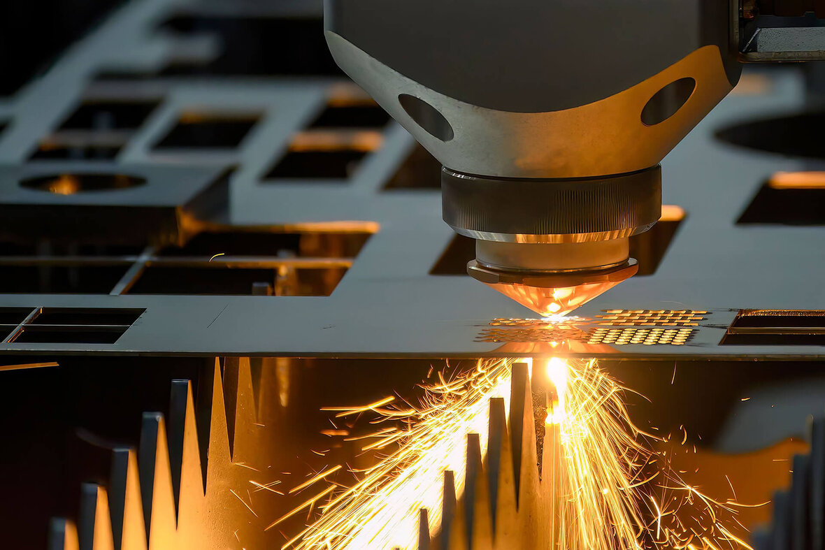 Laserschneidmaschine beim präzisen Schneiden einer Metallplatte mit sichtbaren Funkenflug.